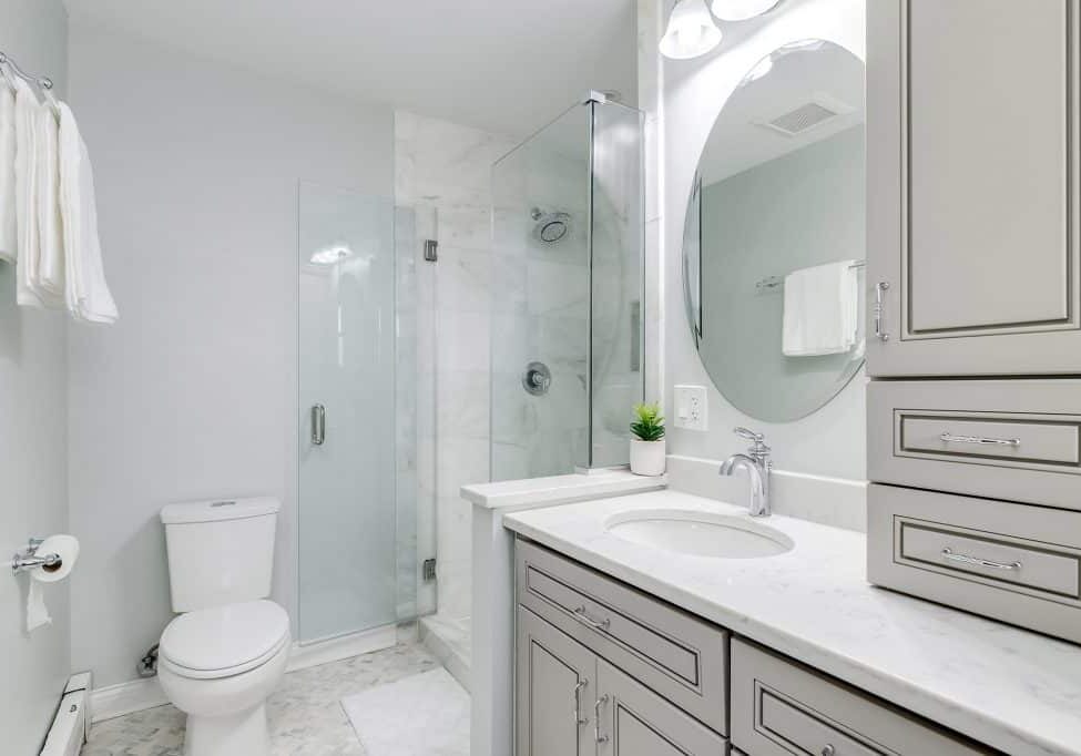 CHICAGO, IL, USA - AUGUST 4, 2020: A remodeled bathroom with a large cabinet aside a marble tiled walk in shower with a glass door.
